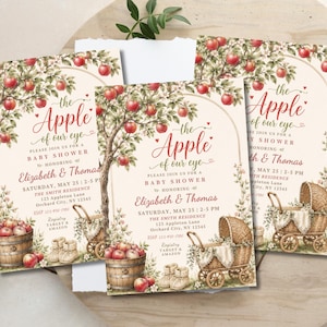 May include: Three rectangular baby shower invitations featuring an apple tree illustration with red apples, a wooden barrel, a wicker baby carriage, and baby booties. The text reads: The Apple of our eye, please join us for a baby shower honouring Elizabeth & Thomas, Saturday, May 25, 2-5 PM, The Smith Residence, 123 Appleton Lane, Orchard City, NY 12345, RSVP 123-456-7890, Registry Target & Amazon.