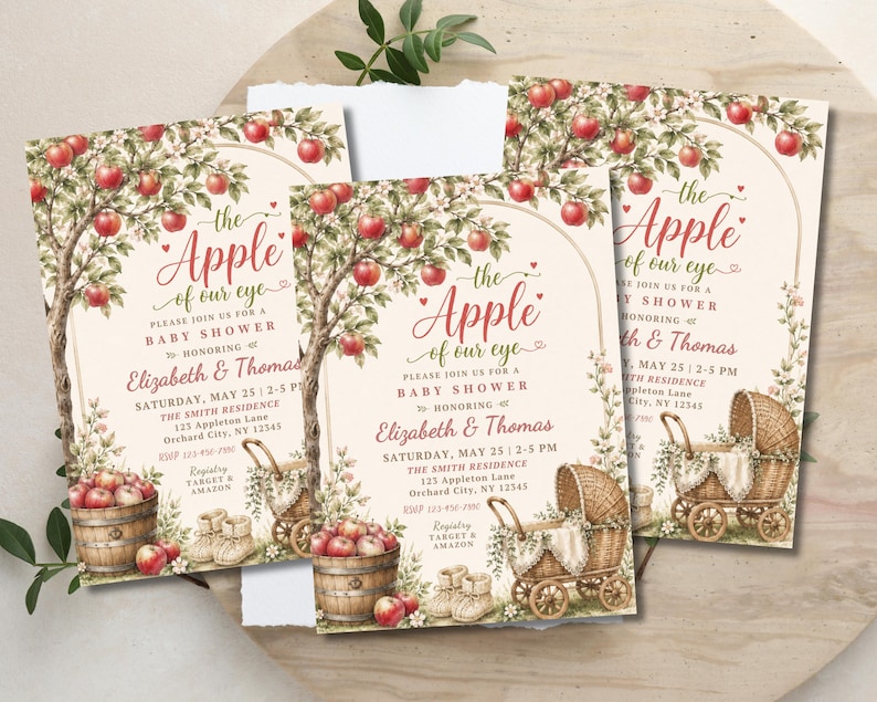May include: Three rectangular baby shower invitations featuring an apple tree illustration with red apples, a wooden barrel, a wicker baby carriage, and baby booties. The text reads: The Apple of our eye, please join us for a baby shower honouring Elizabeth & Thomas, Saturday, May 25, 2-5 PM, The Smith Residence, 123 Appleton Lane, Orchard City, NY 12345, RSVP 123-456-7890, Registry Target & Amazon.