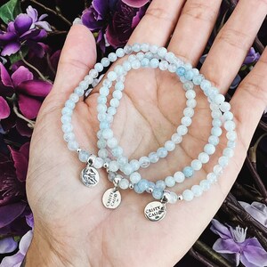 May include: Three delicate aquamarine beaded bracelets with silver charms that read "Christy Calio".