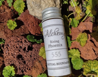 May include: A small glass bottle with a silver lid and a white label. The label says "Alchemy Rising Phoenix 555 Spiritual Bound-Rise".