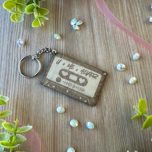 May include: A wooden keychain shaped like a cassette tape with the text "U + ME = FOREVER" and two hearts. The keychain has a silver metal ring.