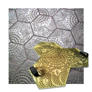 May include: A gold-coloured concrete stamp with a hexagonal design. The stamp features a detailed pattern of flowers and swirls. The stamp is made of durable plastic and has two black straps for easy handling.