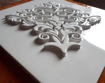 May include: White ceramic wall tile with a raised, embossed design of a floral pattern. The design is intricate and detailed, with swirls and leaves.