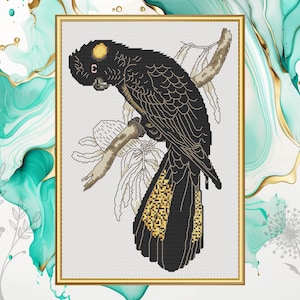 May include: Black and gold cross-stitch pattern of a black cockatoo perched on a branch with leaves. The bird has a yellow crest and a black body with gold accents.