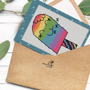 May include: A colorful rainbow-colored popsicle with a black and white striped stick. The popsicle is on a blue card with a white background and the text "Honeyweaver Crafts".