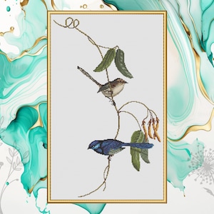 Op de afbeelding: Kruissteekpatroon met twee vogels die op een wijnstok met bladeren zitten. De vogels zijn een blauwe en een bruine winterkoning. Het patroon is in een wit frame met een gouden rand.