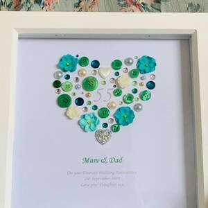 May include: A white frame with a white background and a heart made of green, blue, and white buttons. The number 55 is in the centre of the heart. The text below the heart reads "Mum & Dad On your Emerald Wedding Anniversary 21st September 2019 Love your Daughter xxx"