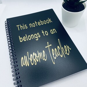 May include: Black spiral notebook with gold lettering that reads "This notebook belongs to an awesome teacher".