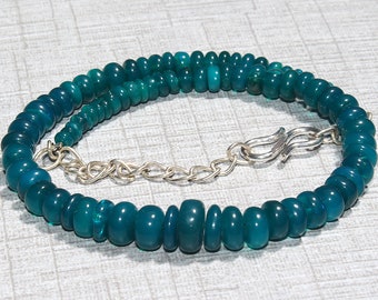 May include: A teal green gemstone necklace with a silver clasp. The necklace is made of round beads and is approximately 18 inches long.