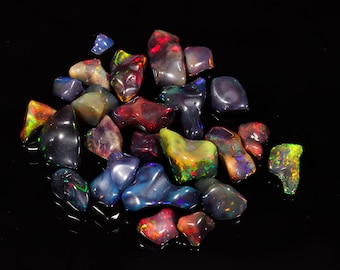 May include: A collection of colorful, iridescent opal gemstones in various shapes and sizes. The opals are arranged on a black background, showcasing their vibrant hues and unique patterns.