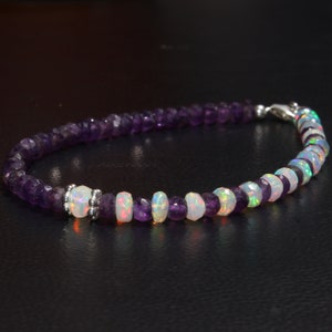May include: A beaded bracelet featuring alternating amethyst and opal gemstones. The bracelet has a silver clasp and is composed of small, faceted purple amethyst beads and iridescent opal beads. The opals display a range of colors.