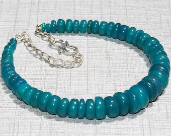 May include: A necklace composed of numerous smooth, round, teal-colored beads with a subtle iridescent sheen. The beads are strung together and feature a silver-toned metal chain with a hook-style clasp at one end for secure fastening.