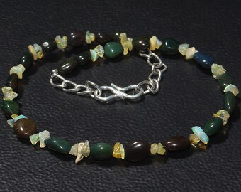 May include: A necklace made of green, brown, and white stones with a silver clasp.