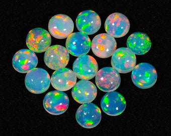 May include: A collection of round, iridescent opal cabochons in various shades of white, blue, green, and pink. The opals are arranged in a circular pattern on a black background.