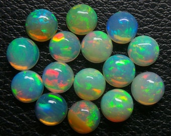 May include: A collection of 15 round, iridescent opal cabochons. The opals are various shades of white, green, and blue with flashes of colour.