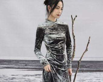 May include: A long-sleeved, gray velvet dress with a mandarin collar and a side slit. The dress has a fitted silhouette and a flowing skirt.