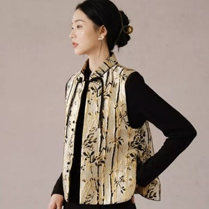 May include: A sleeveless vest with a gold and black floral pattern. The vest has a mandarin collar and a tie closure at the neck.