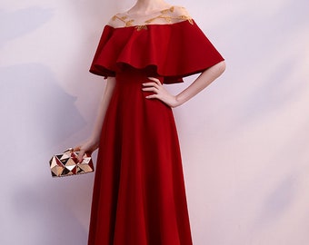 May include: A long, red, formal dress with a ruffled, off-the-shoulder neckline and a sheer, embroidered top.
