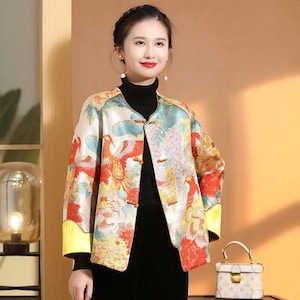 May include: A colorful jacket with a floral and bird print. The jacket has a mandarin collar and a button closure. The sleeves are long and have a yellow trim.