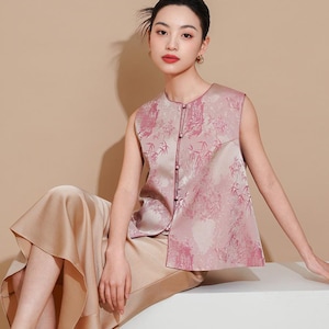 May include: A sleeveless pink and white patterned top with a button-up front. The top has a subtle sheen and features a floral design with bamboo.
