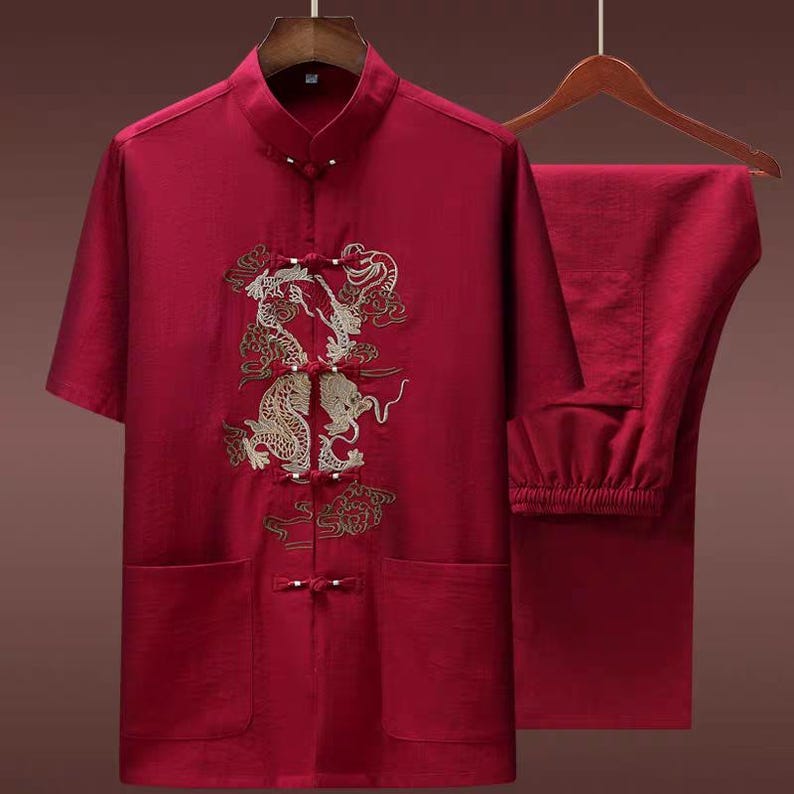 Puede incluir: Un conjunto rojo de estilo chino con una camisa de manga corta y pantalones a juego. La camisa tiene cuello mandar&iacute;n, cierres de rana y bordado de drag&oacute;n dorado. Los pantalones tienen cintura el&aacute;stica.