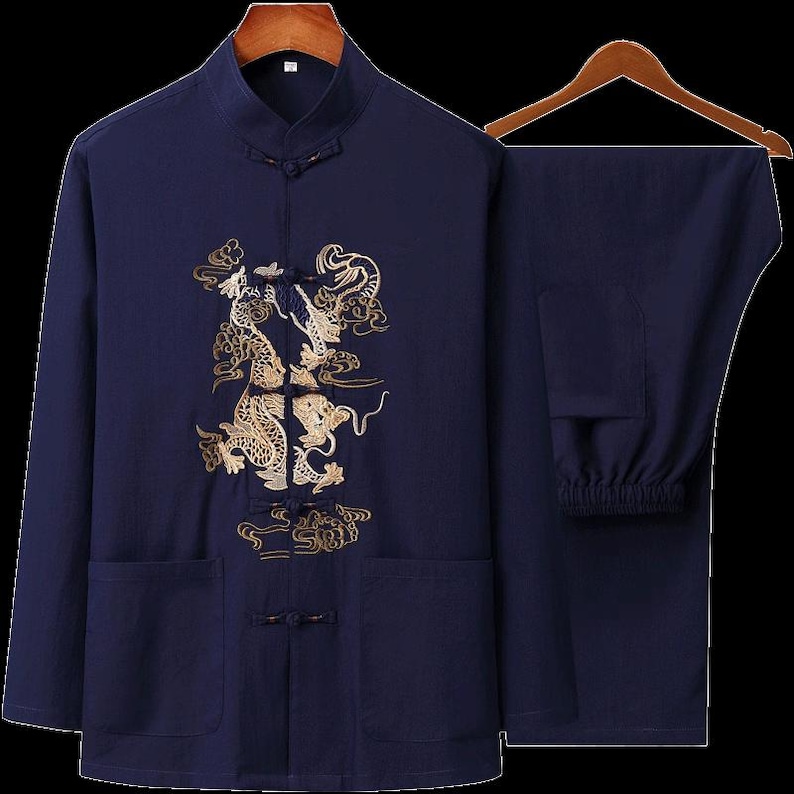 Puede incluir: Traje tradicional chino de dos piezas azul marino. La parte superior de manga larga presenta un cuello mandar&iacute;n y un dise&ntilde;o de drag&oacute;n bordado en oro en la parte delantera. Los pantalones a juego tienen cintura el&aacute;stica. El conjunto se muestra en una percha de madera.