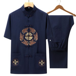 Puede incluir: Conjunto de ropa tradicional china de dos piezas azul marino. La camisa de manga corta presenta un dise&ntilde;o bordado en la parte delantera y dos bolsillos delanteros. Los pantalones a juego tambi&eacute;n son de color azul marino. El conjunto se muestra en una percha de madera.