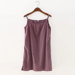 K&ouml;nnte beinhalten: Ein &auml;rmelloses, violettes, Baumwoll-Schlafkleid, das an einem Holzb&uuml;gel h&auml;ngt.