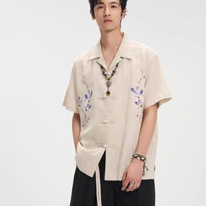 Puede incluir: Un juego de tres tazas de cerámica con un esmalte moteado de color crema. Cada taza presenta un diseño pintado a mano diferente: una hoja azul y verde, una flor amarilla y una baya roja. Las tazas tienen un diseño simple y moderno.