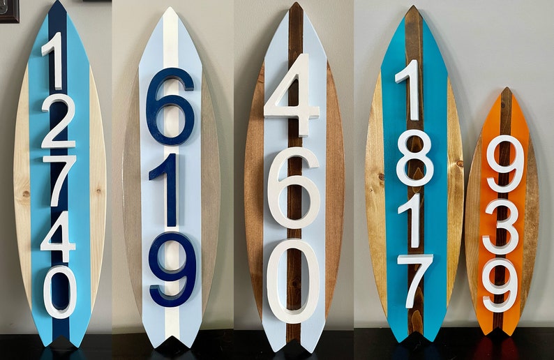 Puede incluir: Cinco letreros de n&uacute;meros de casa de madera con forma de tabla de surf con pintura blanca, azul y marr&oacute;n. Los n&uacute;meros son 12740, 619, 460, 1817 y 939.