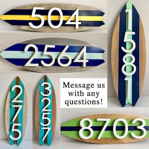 Puede incluir: Conjunto de seis n&uacute;meros de casa de madera con forma de tabla de surf con rayas azules, verdes y amarillas. Los n&uacute;meros son blancos y en relieve. Los n&uacute;meros son 504, 2564, 1581, 275, 3257 y 8703.