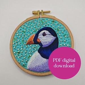 以下が含まれることがあります： 木製のフレームに入った、刺繍されたツノメドリのアートワーク。鳥は白い顔、濃い青色の頭、オレンジ色のくちばしをしています。ターコイズブルーの背景には、緑と金のビーズが飾られています。画像には「PDF digital download」というテキストが含まれています。