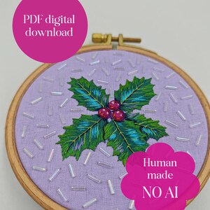 May include: A circular wooden embroidery hoop containing lavender fabric with a hand-stitched holly design featuring green leaves and red berries, accented by scattered iridescent white beads. Text reads: PDF digital download and Human made NO AI.