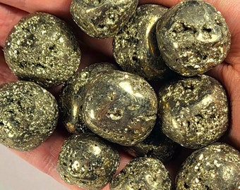 May include: A collection of 10 smooth, round, golden pyrite stones. The stones have a rough, textured surface and are a natural, earthy color.