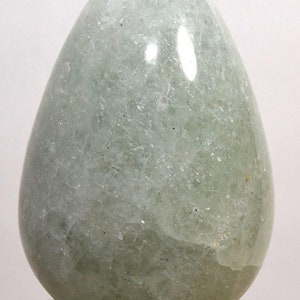 May include: A smooth, light green, egg-shaped crystal. The crystal is polished and has a translucent appearance.
