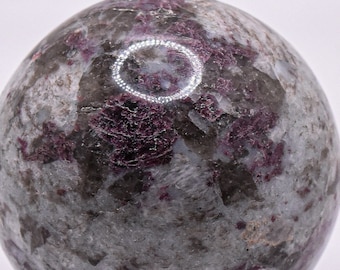 May include: A polished sphere of pink and gray gemstone with a mottled pattern. The sphere is smooth and has a high gloss finish.