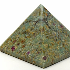 May include: A pyramid-shaped decorative object made of green stone with red and brown inclusions. The pyramid has a square base and a pointed top. The stone has a textured surface and a natural, earthy appearance.