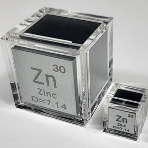 May include: Two clear acrylic cubes containing a silver metal sample labeled "Zn 30 Zinc D=7.14". The larger cube is about twice the size of the smaller cube.