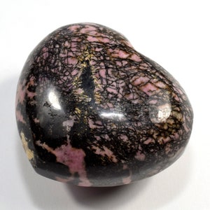 May include: A heart-shaped polished stone with a pink and black pattern. The stone has a smooth, glossy finish and is a natural mineral.