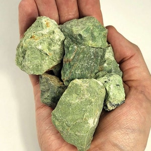 May include: A handful of rough, green serpentine stones. The stones are various sizes and shapes, with a mottled green color.