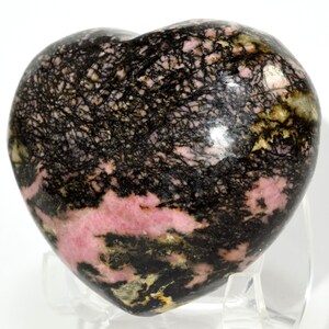 May include: A heart-shaped polished pink and black rhodochrosite crystal with black dendritic inclusions.