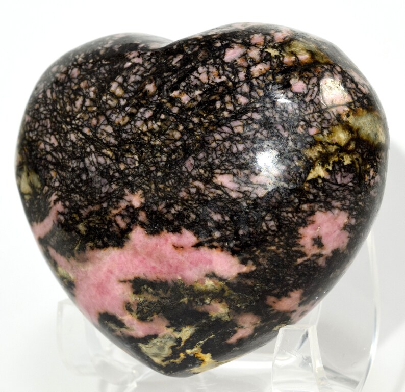 May include: A heart-shaped polished pink and black rhodochrosite crystal with black dendritic inclusions.