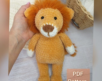 May include: A crocheted lion plush toy with orange fur, white paws, and black eyes. The toy is sitting on a white surface with the text "PDF Pattern" in the lower right corner.