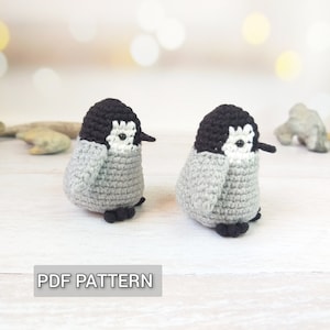 May include: Two crocheted penguin amigurumi toys with black and white details. The penguins are sitting on a white wooden surface. The text "PDF PATTERN" is visible at the bottom of the image.