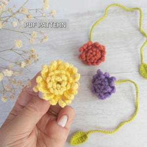 May include: PDF pattern for crocheting three flower bookmarks. The flowers are yellow, orange, and purple. The bookmarks have green leaves.