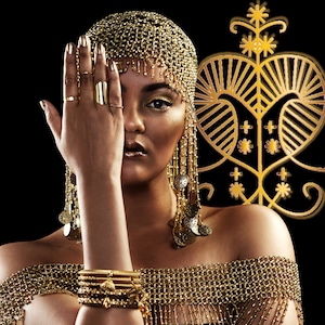 Puede incluir: Una mujer con un tocado dorado y un collar dorado con colgantes en forma de monedas. También lleva pulseras y anillos dorados. El fondo es negro con un diseño dorado.
