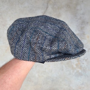 May include: A gray and blue tweed newsboy cap with a herringbone pattern.