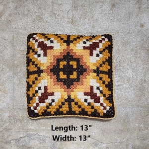May include: A square-shaped cushion with a geometric pattern in shades of brown, yellow, and white. The cushion measures 13 inches in length and 13 inches in width. "Length: 13" and "Width: 13" are printed below the cushion.