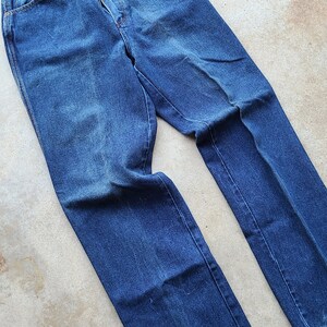 Puede incluir: Un par de pantalones vaqueros azules de denim con corte recto. Los vaqueros tienen un dise&ntilde;o cl&aacute;sico de cinco bolsillos y cierre de bot&oacute;n.