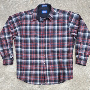May include: A long-sleeved flannel shirt with a red, black, and white plaid pattern. The shirt has a button-down collar and a single chest pocket.